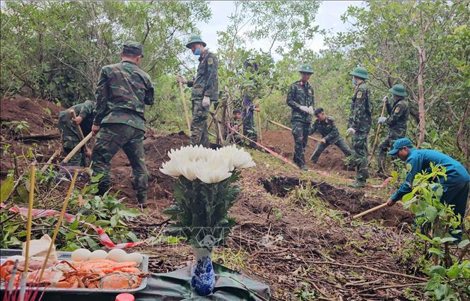 Các chiến sĩ cất bốc, quy tập hài cốt của 3 liệt sĩ trong cùng một ngôi mộ. Ảnh: Công Thử - TTXVN