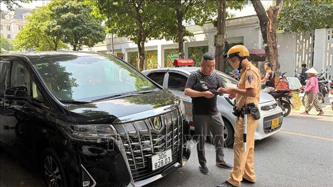 Cán bộ Cảnh sát giao thông lập biên bản xử lý vi phạm, đồng thời hướng dẫn người điều khiển phương tiện chấp hành quy định. Ảnh: Trung Nguyên – TTXVN