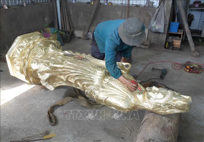 Người thợ thi công hoàn chỉnh tượng đúc bằng đồng, ở cơ sở trên đường Huyền Trân Công Chúa, phường Thuận Hóa, thành phố Huế. Ảnh: Nguyên Lý-TTXVN