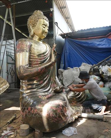 Thợ thi công hoàn chỉnh tượng phật được đúc bằng đồng, ở cơ sở trên đường Huyền Trân Công Chúa, phường Thuận Hóa, thành phố Huế. Ảnh: Nguyên Lý-TTXVN