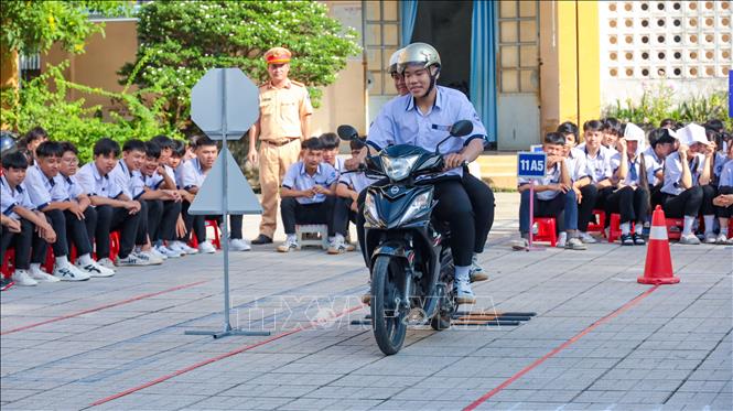 Học sinh Trường Trung học phổ thông Hoàng Văn Thụ, xã Châu Thành, tỉnh Tây Ninh theo dõi phần thực hành kỹ năng lái xe mô tô an toàn trên sa hình. Ảnh: Minh Phú - TTXVN