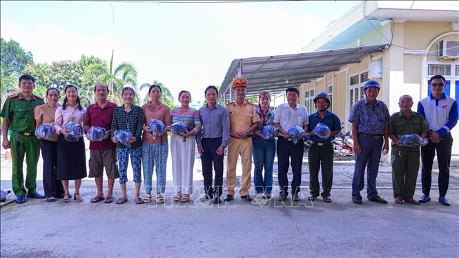 Đại diện lực lượng chức năng, chính quyền địa phương tặng mũ bảo hiểm cho người dân tham gia chương trình. Ảnh: Minh Phú - TTXVN