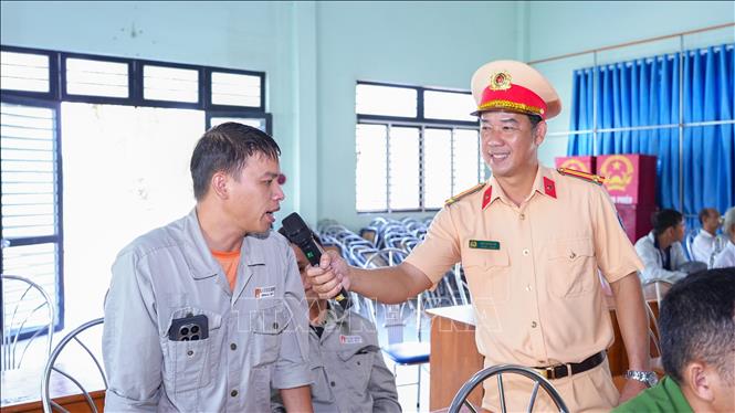Trung tá Cao Thanh Vũ, cán bộ Phòng CSGT Công an tỉnh Tây Ninh trao đổi, hướng dẫn người dân các kiến thức cần thiết khi điều khiển xe mô tô, xe gắn máy, chủ động phòng ngừa nguy cơ tai nạn giao thông. Ảnh: Minh Phú - TTXVN