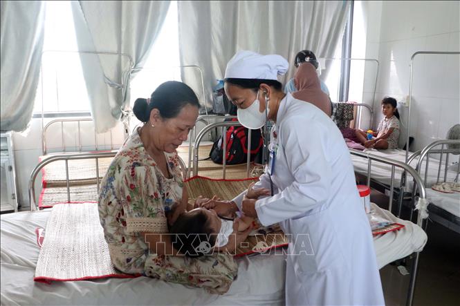 Bác sĩ Bệnh viện Sản Nhi Sóc Trăng thăm khám cho bệnh nhi đang điều trị sốt xuất huyết. Ảnh: Trung Kiên - TTXVN