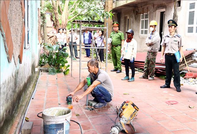Lực lượng chức năng đo đạc, tháo dỡ phần công trình xây lấn, hoàn trả diện tích đất 1,8 m² cho hộ ông Dương Mạnh Hùng. Ảnh: Hoàng Hùng - TTXVN