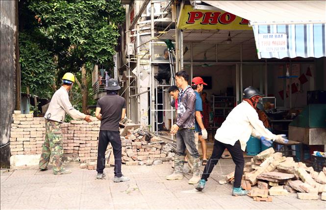 Lực lượng chức năng tháo dỡ công trình xây lấn, cổng sắt và đường ống nước, hoàn trả 1,8 m² đất cho hộ ông Dương Mạnh Hùng theo bản án đã có hiệu lực pháp luật. Ảnh: Hoàng Hùng - TTXVN