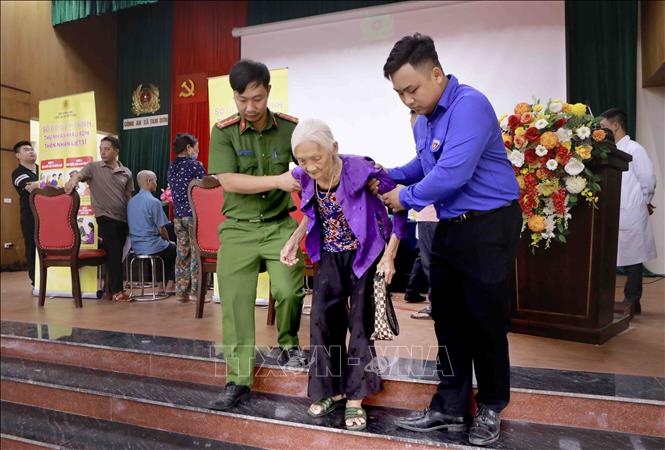 Thanh niên và lực lượng Công an xã hỗ trợ thân nhân liệt sĩ di chuyển tại khu vực lấy mẫu ADN. Ảnh: Hoàng Hùng - TTXVN