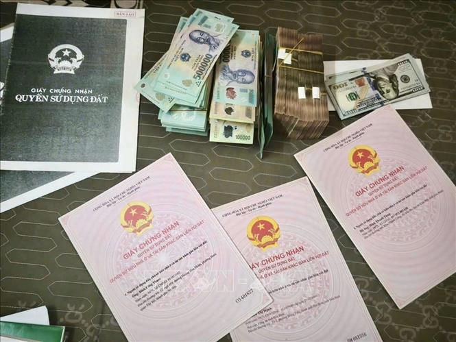 Cơ quan cảnh sát điều tra khám xét, thu giữ giấy chứng nhận quyền sử dụng đất và tiền mặt tại nhà đối tượng Đinh Thanh Tùng. Ảnh: TTXVN phát