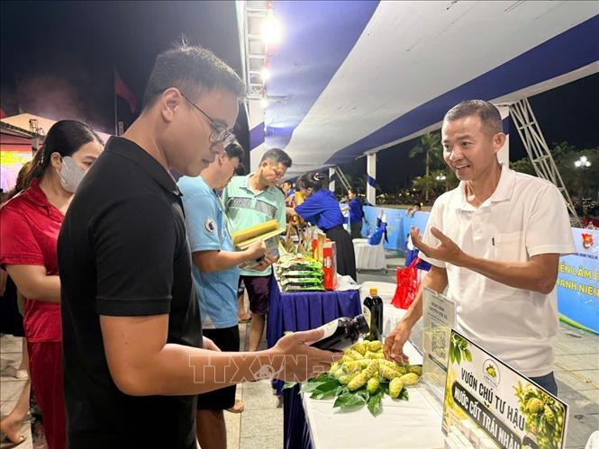 Anh Hà Huy Hậu giới thiệu sản phẩm nước cốt nhàu với người tiêu dùng. Ảnh: Đinh Hương - TTXVN