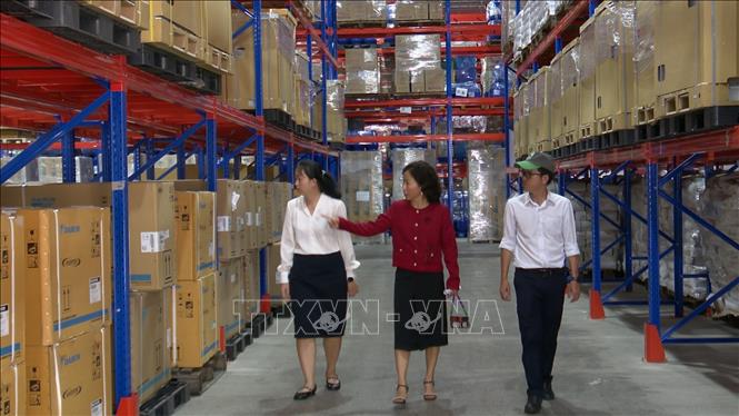 Bà Nguyễn Thị Thảo Ngân (mặc áo đỏ), Phó Tổng Giám đốc Công ty Cổ phần Anpha-AG, tại khu công nghiệp Long Hậu, tỉnh Tây Ninh đang giới thiệu hệ thống lưu trữ hàng hóa trong kho. Ảnh: Thanh Bình –TTXVN