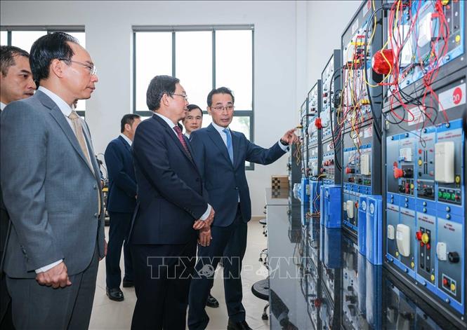 Phó Thủ tướng Hồ Quốc Dũng, Bộ trưởng Bộ Giáo dục và Đào tạo Hoàng Minh Sơn và các đại biểu tham quan máy móc tại Trung tâm thực hành tập trung của Trường Đại học Công nghệ. Ảnh: Hoàng Hiếu - TTXVN 