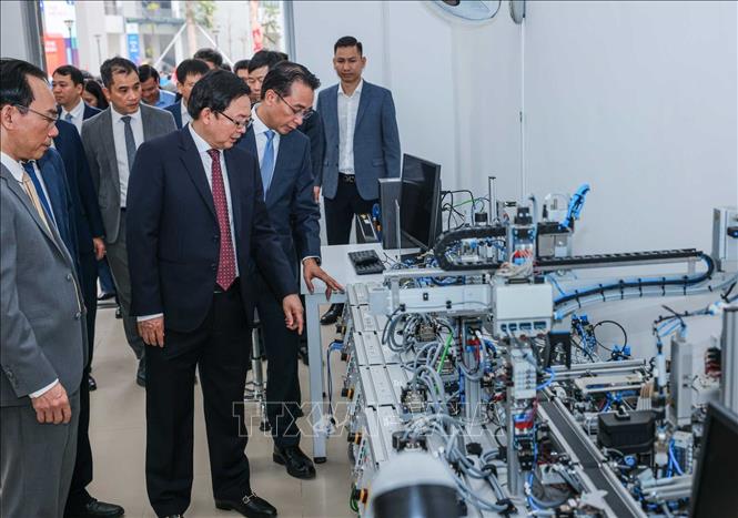 Phó Thủ tướng Hồ Quốc Dũng và các đại biểu tham quan máy móc tại Trung tâm thực hành tập trung của Trường Đại học Công nghệ. Ảnh: Hoàng Hiếu - TTXVN 