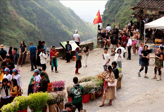 Du khách hào hứng check-in bên ngôi nhà cổ, lưu lại những khoảnh khắc đẹp dưới lá cờ Tổ quốc tung bay giữa Cao nguyên đá. Ảnh: Đức Thọ - TTXVN