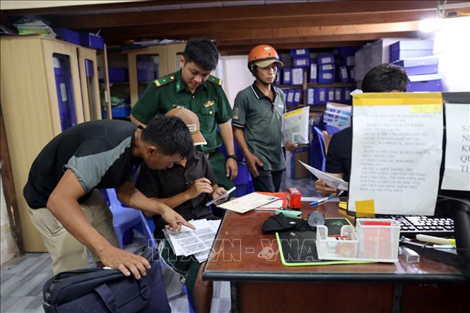 Lực lượng Biên phòng quan sát, sẵn sàng hỗ trợ ngư dân cài đặt, sử dụng phần mềm eCDT (hệ thống phần mềm truy xuất nguồn gốc thủy sản khai thác điện tử) tại cảng cá INCOMAP. Ảnh: Đoàn Mạnh Dương-TTXVN