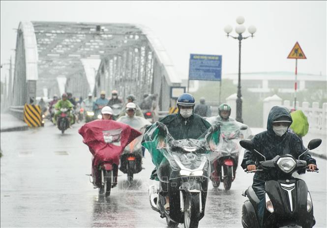 Người dân đi lại trong mưa lớn ở phía Nam cầu Trường Tiền, trung tâm thành phố Huế. Ảnh: Nguyên Lý - TTXVN