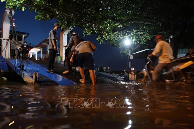 Việc lên xuống phà Bến Đá ẩn chứa nhiều nguy hiểm cho hành khách do nước ngập, trơn trượt. Ảnh: Hồng Đạt - TTXVN
