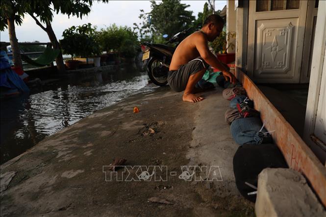 Anh Vũ Hoàng Huy, nhà trên đường Rạch Cùng, làm vách ngăn triều cường lên cao lúc 16 giờ 30 phút ngày 28/10. Ảnh: Hồng Đạt - TTXVN