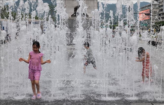 Các em nhỏ chơi đùa bên đài phun nước để tránh nóng tại Seoul, Hàn Quốc. Ảnh: THX/TTXVN phát