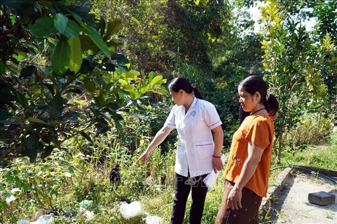 Nhân viên y tế hướng dẫn người dân kiểm tra, loại bỏ các vật dụng có nguy cơ đọng nước quanh nhà. Ảnh: TTXVN phát 