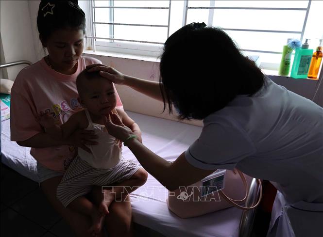 Nhân viên y tế chăm sóc, theo dõi bệnh nhi đang điều trị bệnh tay chân miệng tại khoa Y học nhiệt đới Nhi – Hồi sức tích cực và bệnh lý, Bệnh viện Phụ sản – Nhi Đà Nẵng. Ảnh: Trần Lê Lâm - TTXVN 