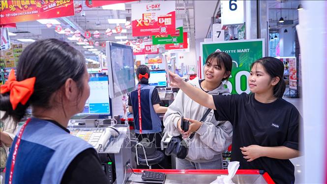 Khách hàng sử dụng điện thoại thông minh thanh toán tại LOTTE MART Tây Ninh. Ảnh: Minh Phú - TTXVN