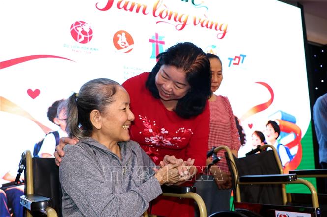 Bà Nguyễn Thị Bích Ngọc, Chủ tịch Hội Bảo trợ Người khuyết tật và Trẻ mồ côi Thành phố Hồ Chí Minh trao tặng xe lăn cho người khuyết tật. Ảnh: Thanh Vũ - TTXVN
