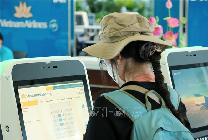 Du khách nước ngoài làm thủ tục check-in tự động tại kios của Vietnam Airlines tại nhà ga T2 sân bay quốc tế Nội Bài. Ảnh: Quốc Khánh - TTXVN