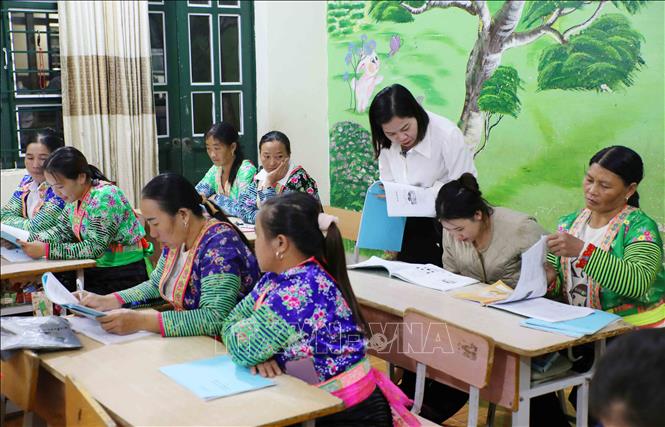 Giáo viên tận tình hướng dẫn từng học viên trong quá trình học tập, giúp phụ nữ dân tộc Mông ở xã vùng cao biên giới tự tin hơn trong hành trình chinh phục con chữ. Ảnh: Trung Kiên - TTXVN