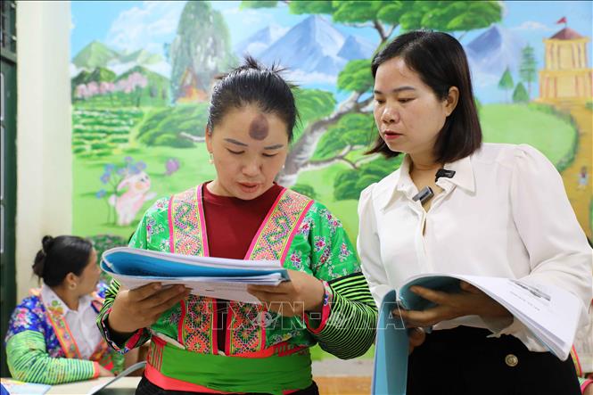 Cô giáo Nông Thị Mậu hướng dẫn học viên Sình Thị Nếnh đọc bài. Ảnh: Trung Kiên - TTXVN