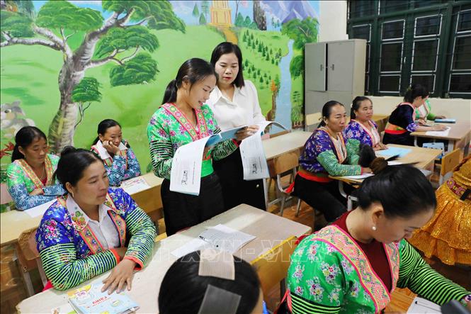 Giáo viên hướng dẫn học viên đọc bài, luyện tập kỹ năng đọc cho các học viên là phụ nữ dân tộc Mông tại xã Sam Mứn, tỉnh Điện Biên. Ảnh: Trung Kiên - TTXVN