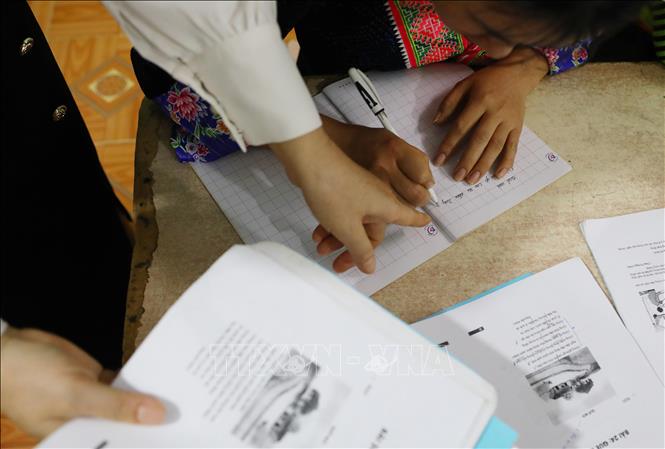 Giáo viên tận tình hướng dẫn từng học viên trong quá trình học tập, giúp phụ nữ dân tộc Mông ở xã vùng cao biên giới tự tin hơn trong hành trình chinh phục con chữ. Ảnh: Trung Kiên - TTXVN